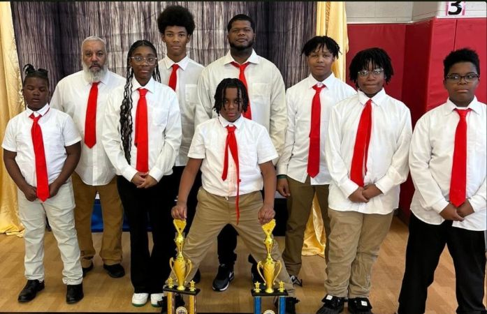  Boys and girls dressed in white shirts and black pants with a red tie, standing with a chess trophy